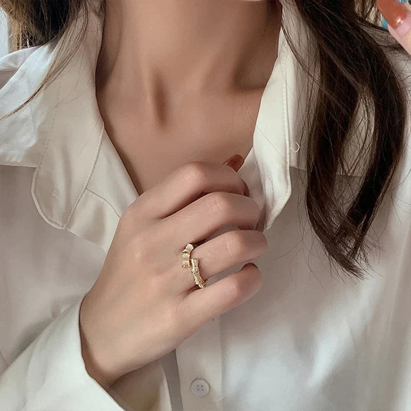 Frau trägt goldenen Ring, elegantes Schmuckdesign, weiße Bluse, modisches Accessoire.