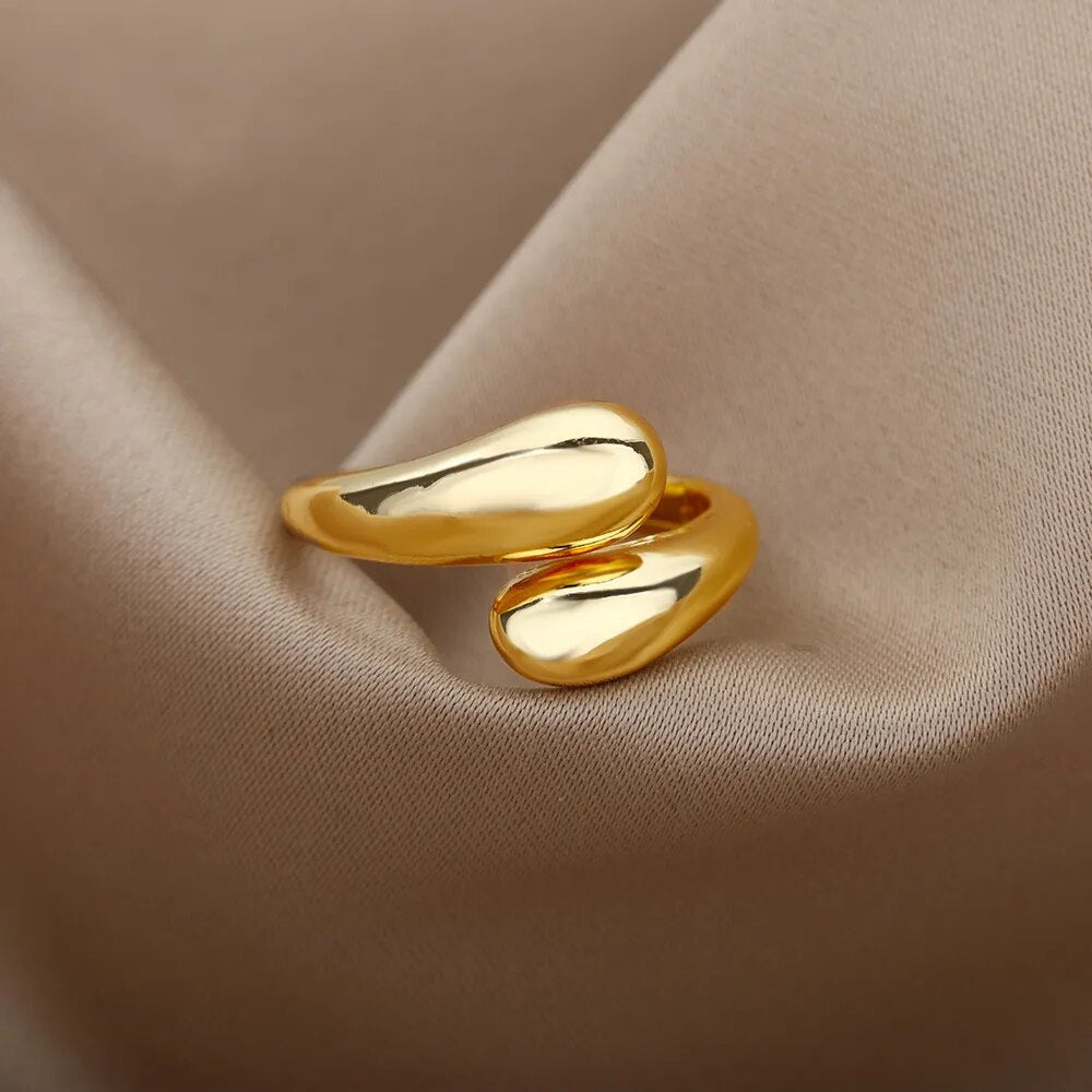 Goldener, geschwungener Ring auf beigem Stoff, elegantes Schmuckdesign, glänzend, modern.