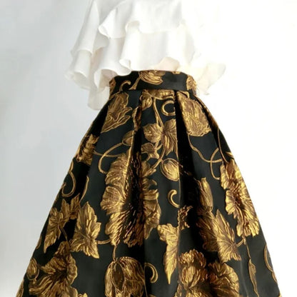 Weißes Rüschenoberteil und schwarzer Rock mit goldenen Blumenmuster, elegantes Damenoutfit.