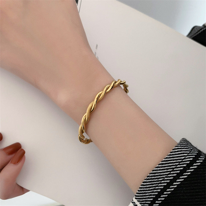 Goldener Twist-Armreif aus Edelstahl, Damen-Schmuck, elegantes Design, modisches Accessoire.