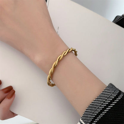 Goldener Twist-Armreif aus Edelstahl, Damen-Schmuck, elegantes Design, modisches Accessoire.
