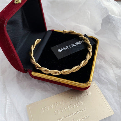 Goldener Edelstahl-Twist-Armreif in Schmuckschatulle, elegantes Damen-Accessoire.