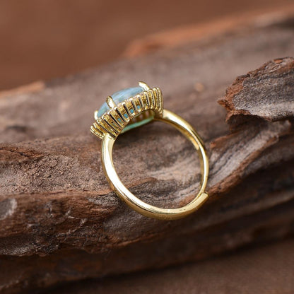 Goldener Verlobungsring mit blauem Opal und Zirkon, verstellbar, auf Holz präsentiert.