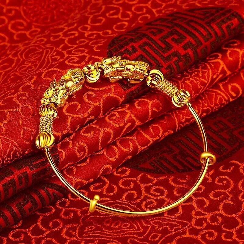 Goldenes Armband mit Drachenmotiv auf rotem Seidenstoff, traditionelles chinesisches Design.