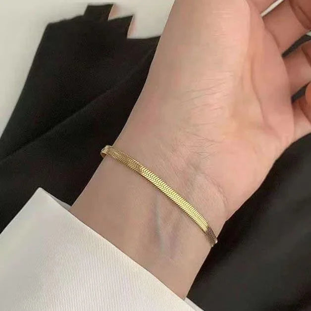 Goldenes Armband am Handgelenk, elegantes Schmuckstück, minimalistisch, modisch, Damenaccessoire.