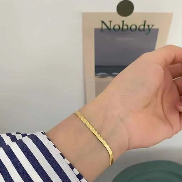 Goldenes Armband am Handgelenk, minimalistisch, elegantes Schmuckdesign, Nahaufnahme.
