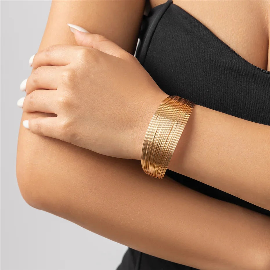 Frau trägt elegantes, goldenes Armband aus Metall, modisches Accessoire, Nahaufnahme.