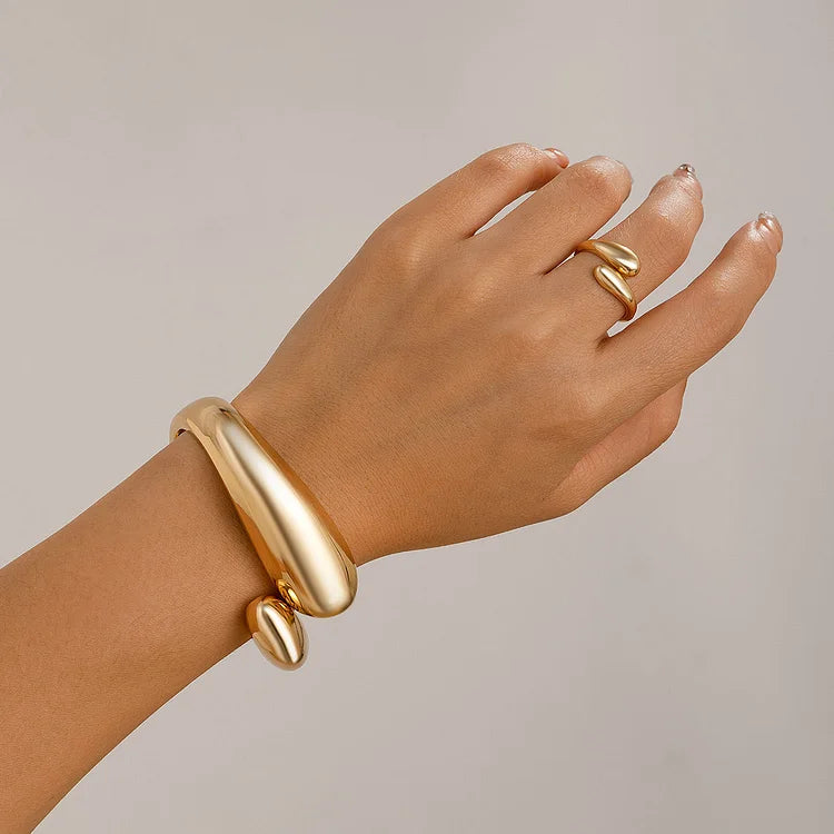 Goldenes Armband und Ring auf Hand, modernes Schmuckdesign, eleganter Modeschmuck, minimalistisch.
