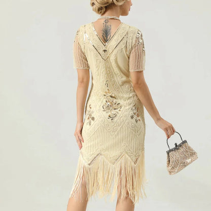 Frau in cremefarbenem Fransen-Kleid mit Pailletten, Vintage-Stil, hält eine kleine Tasche.