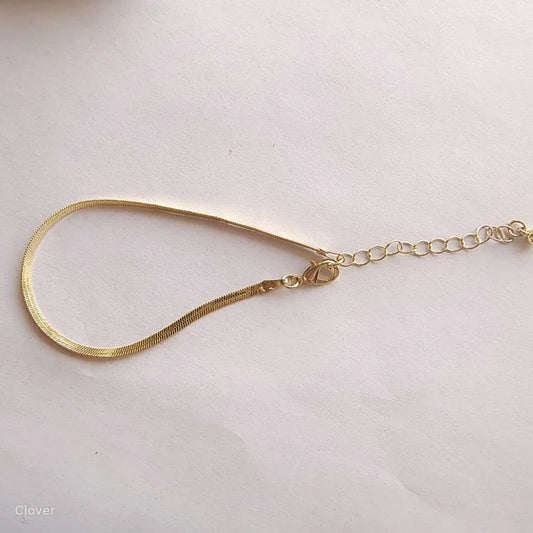 Goldenes Schlangenarmband mit verstellbarem Verschluss auf weißem Hintergrund, eleganter Schmuck.