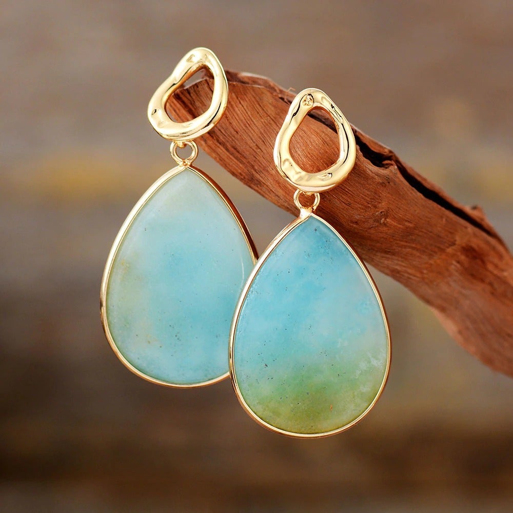 Goldene Ohrringe mit blauen Tropfenanhängern, eleganter Schmuck für Damen.