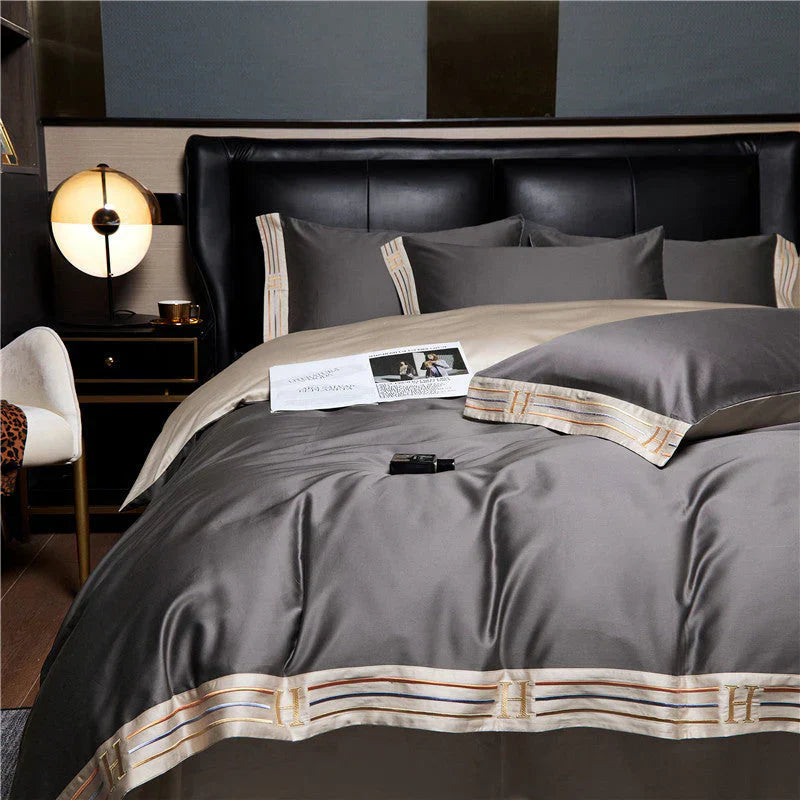 Luxuriöse graue Bettwäsche-Set aus Satin mit Kissenbezügen und dekorativen Streifen im Schlafzimmer.