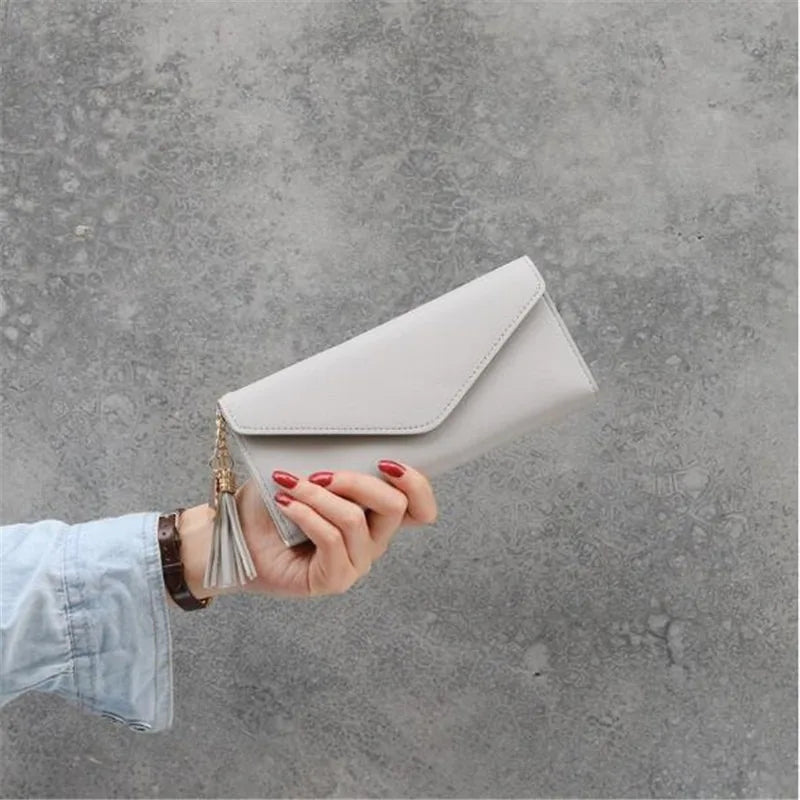Damenhandtasche aus grauem Leder mit Quaste, elegantes Design, modisches Accessoire.