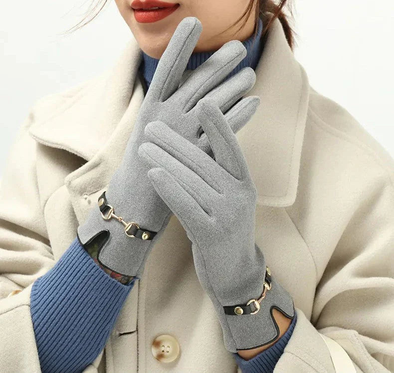 Frau trägt graue Wollhandschuhe mit goldenen Details, eleganter Wintermantel, modisch warm.