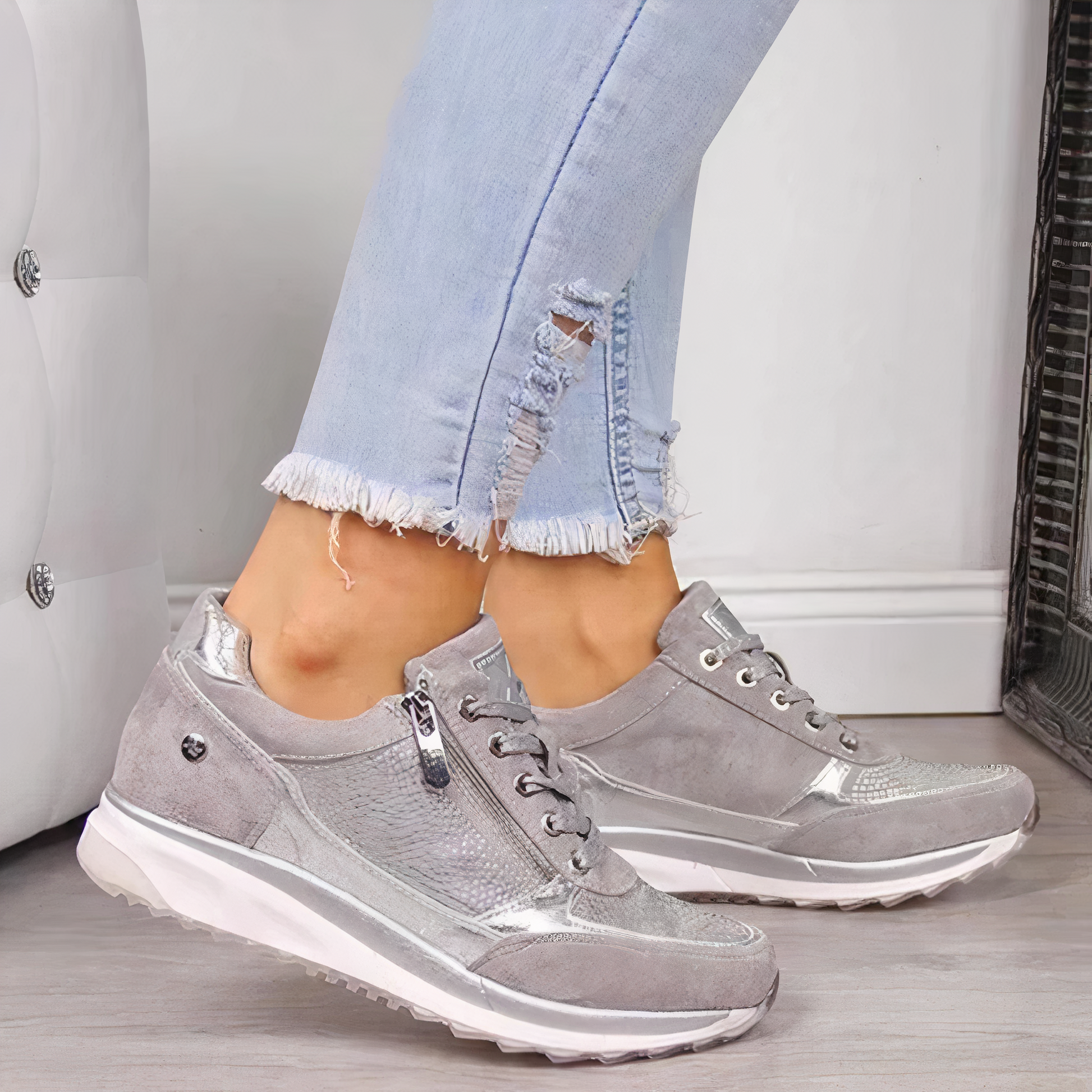 Graue Damen-Sneaker mit silbernen Details, kombiniert mit hellblauen Jeans, modisch und bequem.