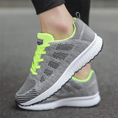 Graue Damen-Laufschuhe mit neongelben Akzenten, atmungsaktives Mesh, rutschfeste Sohle.