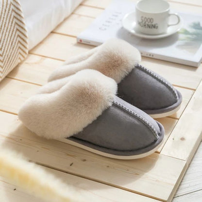 Graue Hausschuhe mit weißem Fellfutter auf Holzfußboden, gemütliche Winterpantoffeln.