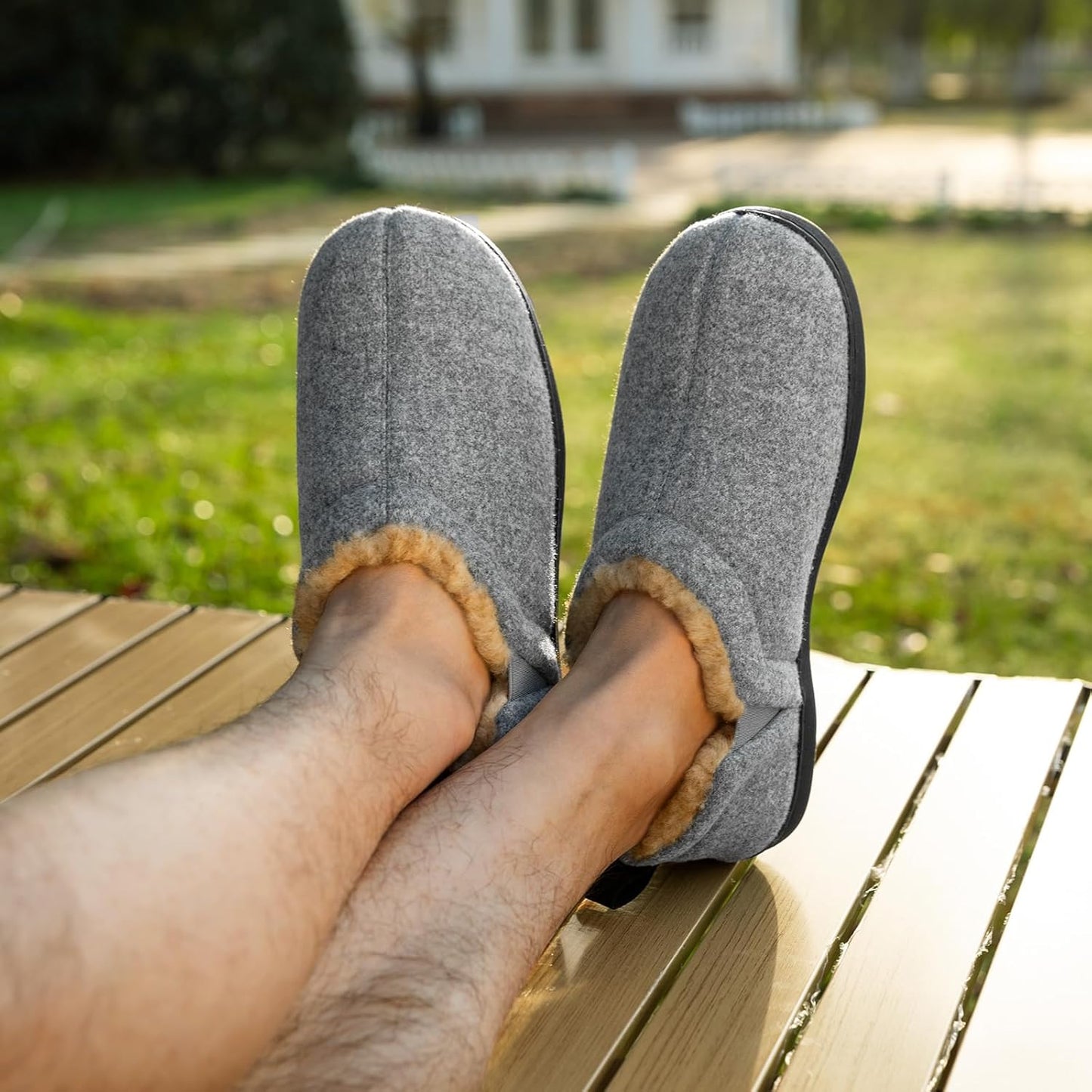 Graue Filzhausschuhe mit Fellfutter, Herren, bequem, auf Holzterrasse im Freien.