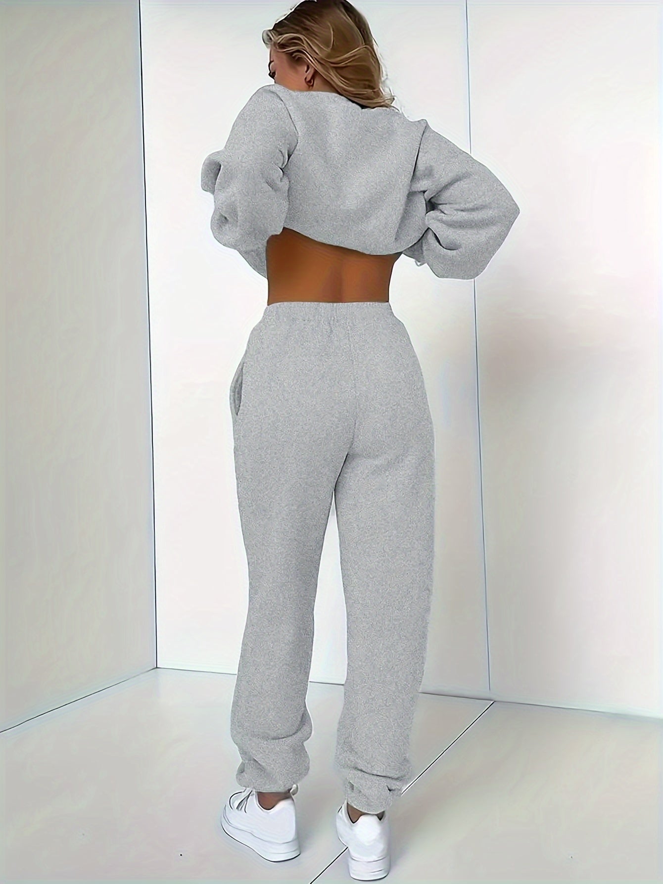 Frau in grauem Jogginganzug, Rückenansicht, Sportbekleidung, gemütlich, modisch, Indoor.