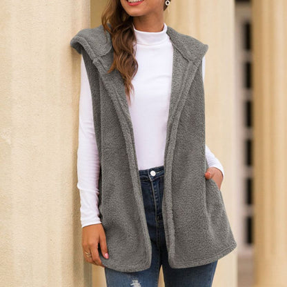 Frau trägt graue Fleeceweste mit Kapuze, weiße Bluse, blaue Jeans, lässige Herbstmode.