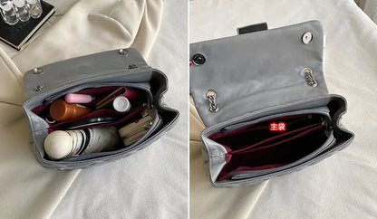 Graue Handtasche aus Leder, geöffnet, mit Kosmetikartikeln und Geldbörse, auf beigem Stoff.