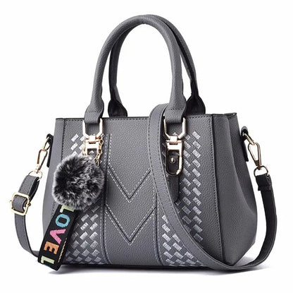 Graue Damenhandtasche mit Schulterriemen, Kunstleder, Pompon-Anhänger, modisches Design.