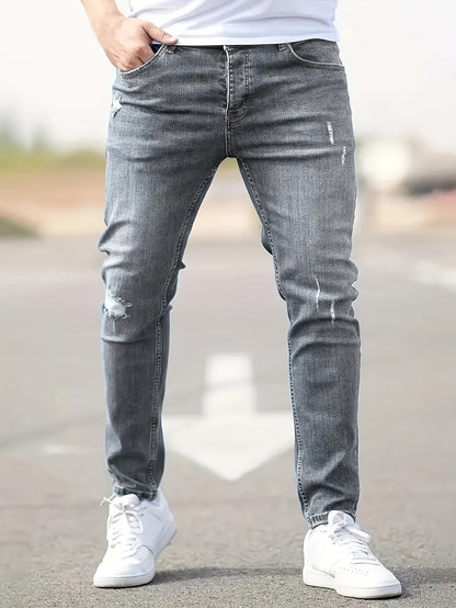 Graue Herren-Jeans, Slim Fit, mit leichten Rissen, getragen mit weißen Sneakern auf Straße.