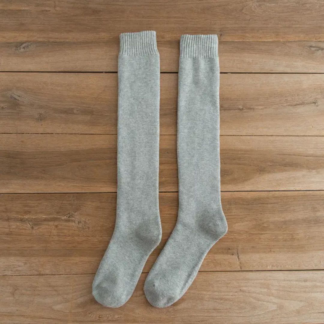 Graue Kniestrümpfe aus Baumwolle auf Holzboden, bequeme Socken für Damen und Herren.