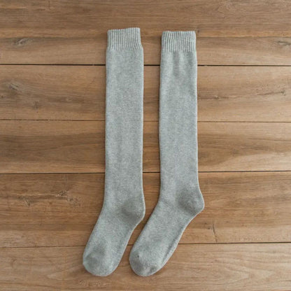 Graue Kniestrümpfe aus Baumwolle auf Holzboden, bequeme Socken für Damen und Herren.