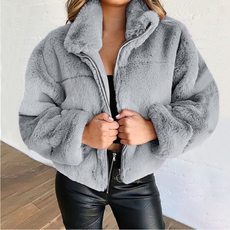 Frau in grauer Kunstpelzjacke, Reißverschluss, schwarze Lederhose, modisch, Winterkleidung.