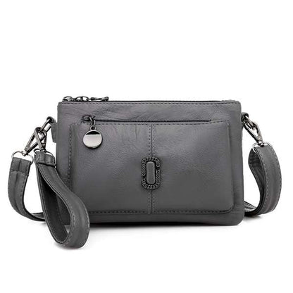 Graue Leder-Umhängetasche mit Reißverschluss, verstellbarem Riemen und silbernen Details.