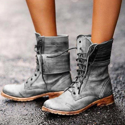 Graue Lederstiefel für Damen, geschnürt, modisch, robust, auf nasser Straße.