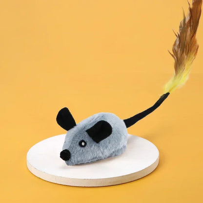 Graues Katzenspielzeug Maus mit Federschwanz auf gelbem Hintergrund.