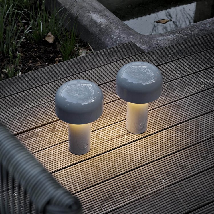 Zwei graue LED-Pilzlampen auf Holzterrasse im Freien, moderne Gartenbeleuchtung.
