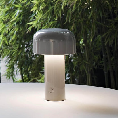 Graue Tischlampe aus Keramik, modern, auf weißem Tisch vor Bambus, stilvolle Beleuchtung.