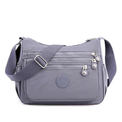 Graue Umhängetasche aus Nylon mit Reißverschlüssen, verstellbarem Gurt, Damenmode Accessoire.