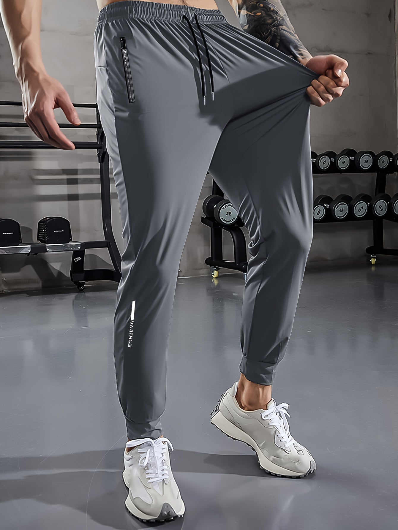 Graue Herren-Trainingshose, elastisch, mit Reißverschlusstaschen, im Fitnessstudio.