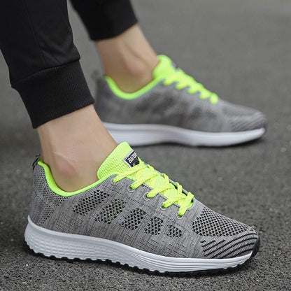 Graue Sportschuhe mit neon-gelben Schnürsenkeln, atmungsaktiv, für Herren, auf Asphalt.