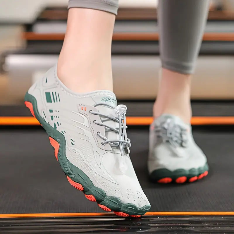 Graue Sportschuhe mit grünen und orangefarbenen Akzenten auf Laufband, ideal für Fitness und Laufen.