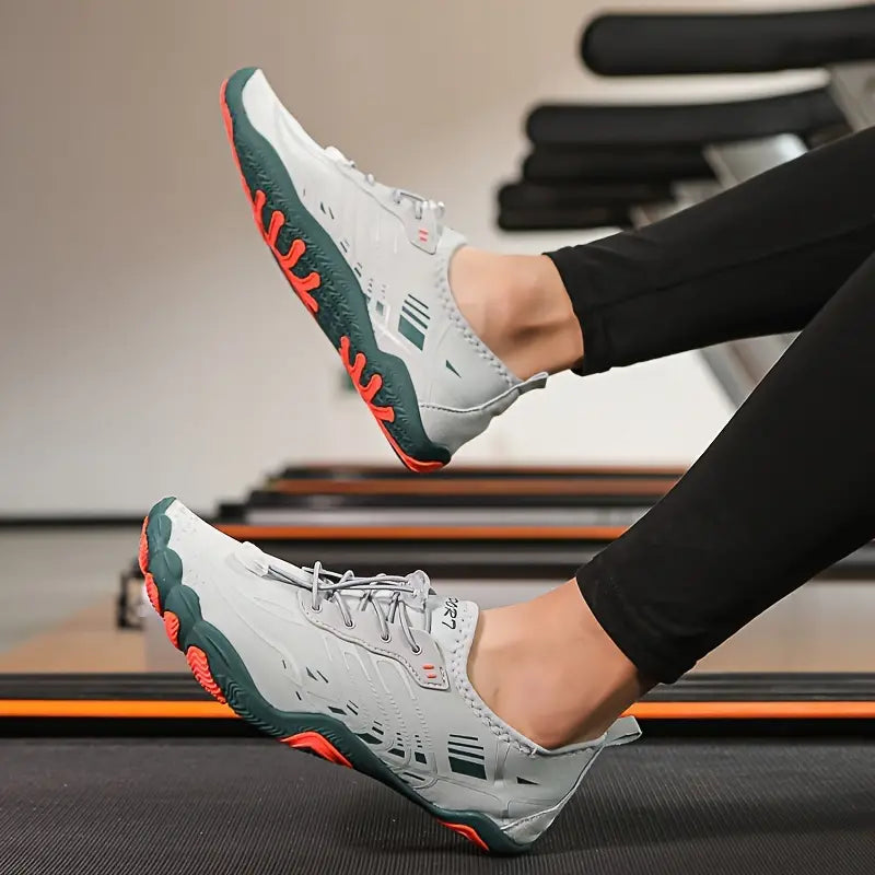 Graue Sportschuhe mit roter Sohle, ideal für Fitness und Laufen, auf Laufband getragen.