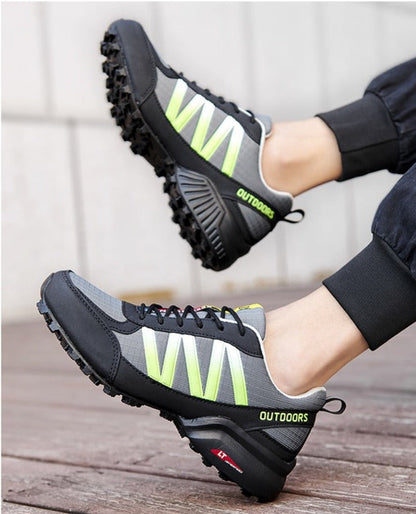 Graue und schwarze Outdoor-Laufschuhe mit gelben Akzenten, rutschfeste Sohle, sportlich.