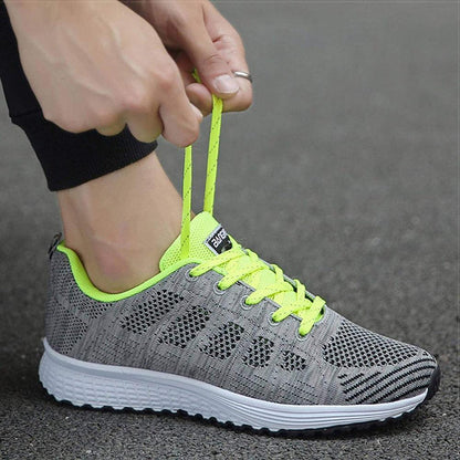 Grauer Sportschuh mit neongelben Schnürsenkeln, atmungsaktiv, ideal zum Laufen.