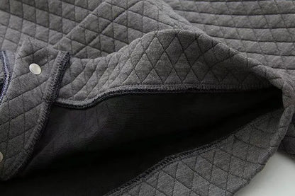 Grauer gesteppter Stoff, weiche Textur, ideal für Bekleidung, Heimtextilien, hochwertig.