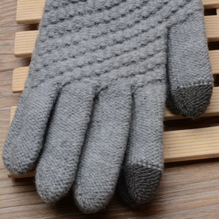 Grauer gestrickter Handschuh aus Wolle auf Holzuntergrund, winterfest, warm, stilvoll.