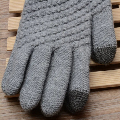 Grauer gestrickter Handschuh aus Wolle auf Holzuntergrund, winterfest, warm, stilvoll.