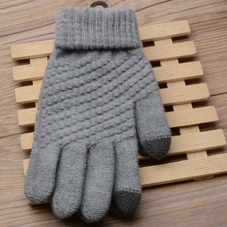 Grauer Strickhandschuh aus Wolle mit Touchscreen-Funktion, auf Holzuntergrund.