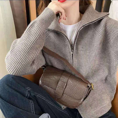 Frau mit grauem Strickpullover und brauner Lederhandtasche, modisch, elegant, Herbstmode.