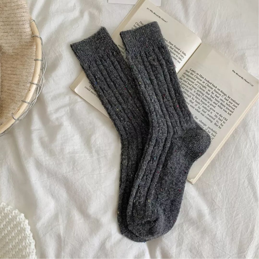Graue Wollsocken auf Buch, gemütlich, warm, Strick, Wintermode, Accessoire, Bettwäsche.