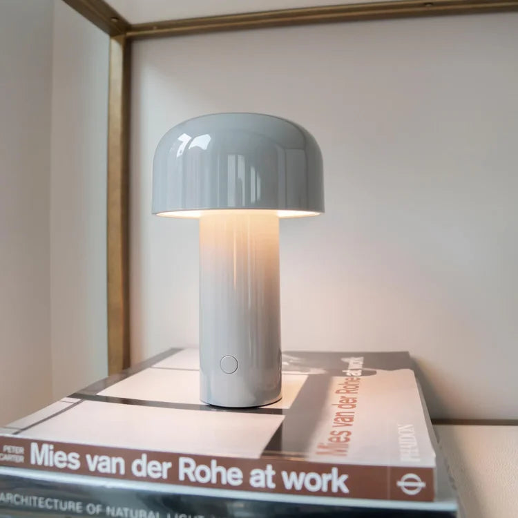 Graue Tischlampe aus Keramik auf Bücherstapel, modernes Design, Innenbeleuchtung.