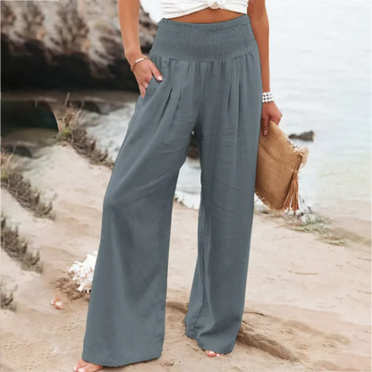 Frau in grauer Leinenhose am Strand, Sommermode, lässige Damenbekleidung, Strandhintergrund.